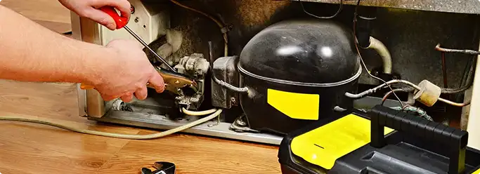 Refrigerator repair technician fixing the compressor and wiring in Mira Loma, CA