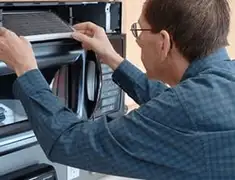 Appliance repair technician replacing a microwave vent filter in Riverside, CA