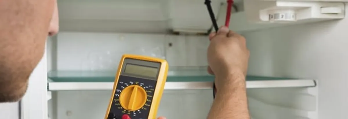 Refrigerator repair technician testing electrical components with a multimeter in Riverside, CA