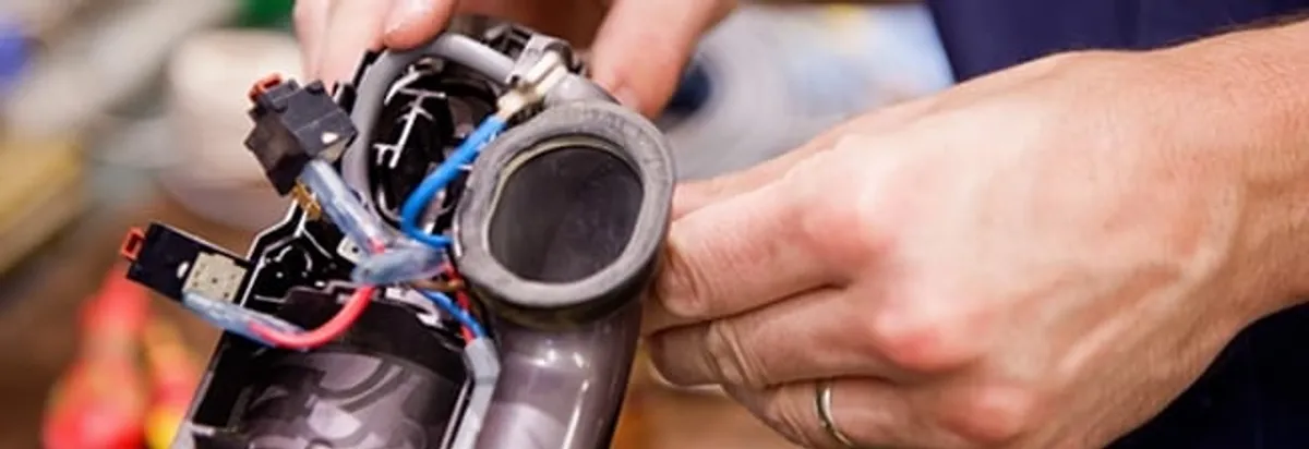 Vacuum repair technician reconnecting wiring and components in Riverside, CA